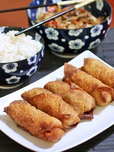 some food is on a white plate with chopsticks and rice in the bowl