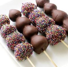 chocolate covered donuts and sprinkles on a white plate with toothpicks