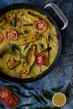 a pan filled with food on top of a wooden table next to green beans and tomatoes