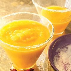 two glasses filled with orange juice on top of a table