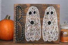 a wooden sign with two shoes on it next to some pumpkins and a candle