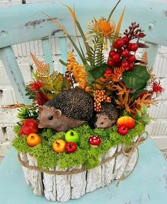 two hedgehogs sitting on top of a wooden basket filled with fruits and vegetables