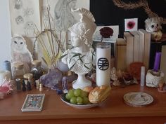 a table topped with a vase filled with grapes and bread next to other items on top of a wooden table