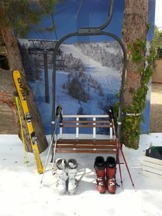 skis and snowboards are lined up in front of a bench