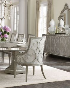 an elegant dining room with chandelier and white chairs in front of the table