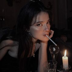 a woman sitting at a table with a candle in her mouth