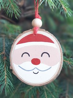 a wooden ornament hanging from a tree with a santa clause face on it