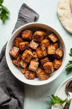 a white bowl filled with tofu and garnished with parsley on the side