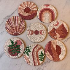 six coasters with designs on them sitting on a marble countertop in the shape of seashells