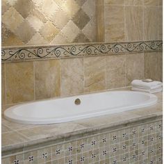 a bath tub sitting next to a tiled wall in a bathroom with beige and white tiles