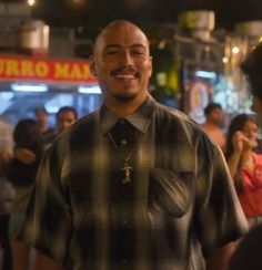 a man smiling while standing in front of a group of people at an outdoor event