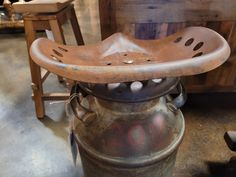 an old metal bucket sitting on top of a wooden table next to a chair and other furniture