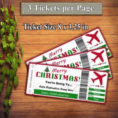 three tickets for christmas are sitting on a wooden table next to a plant with green leaves