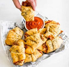 a person dipping sauce on top of pastries