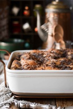 a casserole dish is sitting on a table next to silverware and an old - fashioned tea kettle