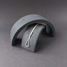 an object made out of concrete with a chain on it's end, sitting on a gray surface