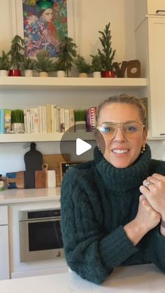 a woman wearing glasses sitting at a kitchen counter