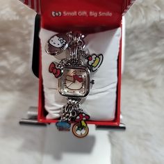 a hello kitty watch in a red box on a white furnishing area with an attached chain