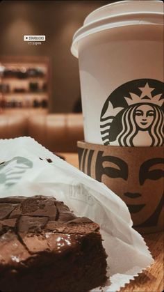 a piece of chocolate cake sitting next to a cup of coffee on top of a table