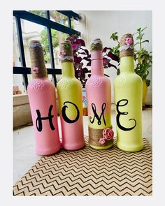 three pink and yellow bottles with the word home painted on them sitting next to each other