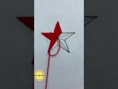 an origami star on a white piece of paper with a red string attached to it