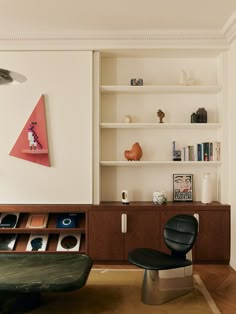 a living room filled with furniture next to a book shelf and shelves on the wall