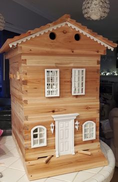 a wooden dollhouse with white windows and shutters