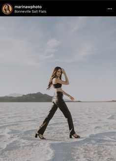 a woman is walking in the desert wearing high heels and a cropped bra top