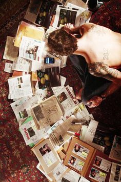 a man sitting on top of a pile of papers next to a table with pictures