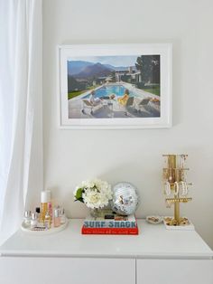 a white dresser topped with lots of drawers and vases next to a swimming pool