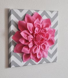 a pink flower is mounted on a gray and white chevroned wall art piece