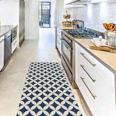 a kitchen with an area rug on the floor next to the stove and cabinets in it