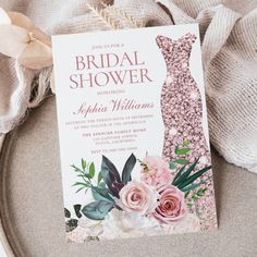 a bridal shower card with pink flowers and greenery sits on top of a plate