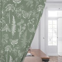 a green curtain with white flowers and butterflies on it in a living room area next to a coffee table