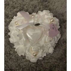 a white heart shaped brooch with pearls and flowers on it's centerpiece