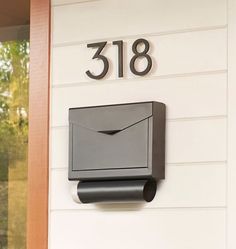 a mailbox mounted to the side of a house with an envelope in front of it