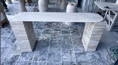 a stone table sitting on top of a tiled floor next to two large vases