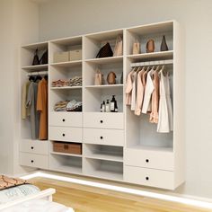 a white closet with drawers and clothes hanging on the wall next to a bed in a room