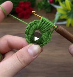 someone is holding a green crochet piece with a hook in it and the yarn has been hooked up