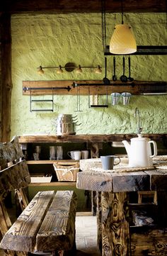 a rustic kitchen with green walls and wooden benches