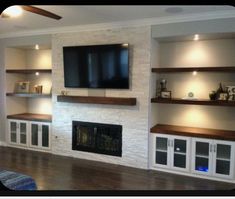 a living room with built in shelves and a flat screen tv