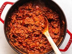 a large pot filled with chili and a wooden spoon in the bottom one side is red