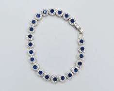 Incredibly elegant 925 Sterling Silver tennis bracelet with 23 total pieces, a stunning royal blue center stone, surrounded by nine clear cubic zirconia stones. This bracelet is stylish, sparkly and made to look like real diamonds and sapphires. It's design will really turn heads and is ideal for a special occasion such as a wedding or event. - Bracelet Size: 17.5cm long - Bracelet Width: 6.5mm - Bracelet closure: secure clasp - Hallmarked 925 for solid sterling silver. 🌸 We have more sterling Sapphire Cubic Zirconia Tennis Bracelet, Blue Round Crystal Bracelet For Formal Occasions, Elegant Blue Cubic Zirconia Crystal Bracelet, Blue Cubic Zirconia Crystal Bracelet, Formal Blue Round Crystal Bracelet, Elegant Blue Crystal Bracelet With Sparkling Stones, Blue Cubic Zirconia Bracelet With Sparkling Stones, Elegant Blue Bracelets With Rhinestones, Elegant Blue Rhinestone Bracelets