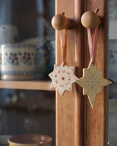 two wooden ornaments hang from the side of a door handle in front of a bowl