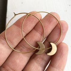 Crescent Moon Hoop EarringsThese light weight solid brass hoop earrings are the perfect accessory to finish an ensemble. Their warm golden hue catches the light and gives a little sparkle to your day.Also available in silver plated with stainless steel hoops. ➳ ITEM DETAILS:Hoop width: 1.25 inchesAll earring parts are solid brass✈ + ✉ SHIPPING / POLICIES:This listing is for one pair of earrings and they ships from Vancouver, Canada.Please see my shop policies for more details:https://www.etsy.co Gold Crescent Hoop Earrings For Everyday, Everyday Gold Crescent Hoop Earrings, Celestial Gold Dangle Hoop Earrings, Gold Half Moon Celestial Earrings, Minimalist Brass Half Moon Jewelry, Minimalist Half Moon Brass Jewelry, Gold Moon Shaped Metal Hoop Earrings, Gold Moon-shaped Metal Hoop Earrings, Nickel-free Moon Shaped Hoop Earrings