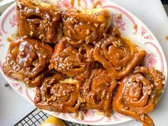 a white plate topped with cinnamon rolls covered in caramel