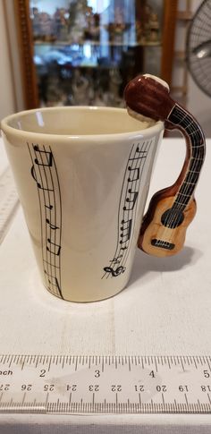 a ceramic cup with musical notes on it and a wooden instrument sticking out of the top