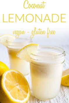 two glasses filled with lemonade sitting on top of a table next to sliced lemons