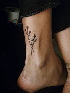 a woman's foot with a small tattoo on it that has flowers growing out of it