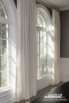 an empty room with white curtains and windows